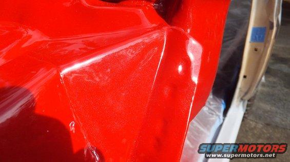 Red metallic fender and door edge with blue tape on door jamb
