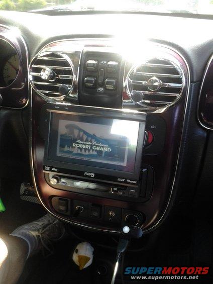 Dashboard of a car with a touchscreen, radio, and air vents. A video is playing on the screen