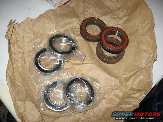 Bearings on brown paper, some in plastic packaging, others with red seals