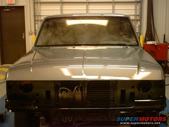 Pickup truck front end, missing grille and headlights, in a workshop