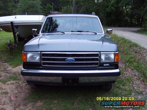 Front view of a gray Ford F-Series truck, parked outside with a boat on a trailer behind it