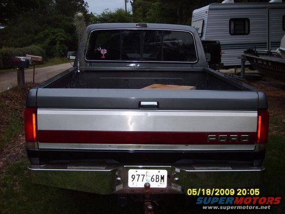 Gray Ford F-150 pickup truck rear view, chrome bumper, red and silver tailgate stripe