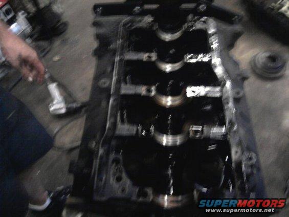 Engine crankshaft and block with oil, a hand holding a tool is visible on the left