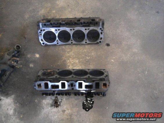 Two engine cylinder heads sitting on a concrete floor