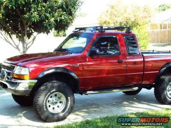 Red 1999 Ford Ranger pickup truck with roof rack and off-road tires