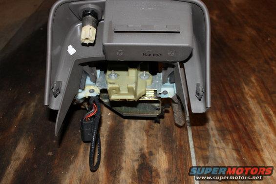 Gray plastic car interior component with exposed wiring and mechanical parts