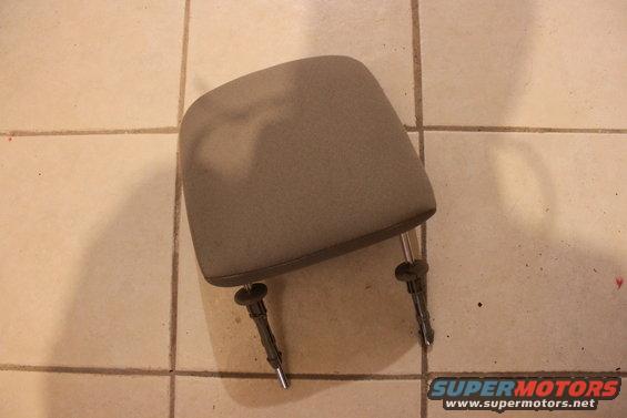 Gray fabric headrest with metal posts and black plastic clips on a tiled floor