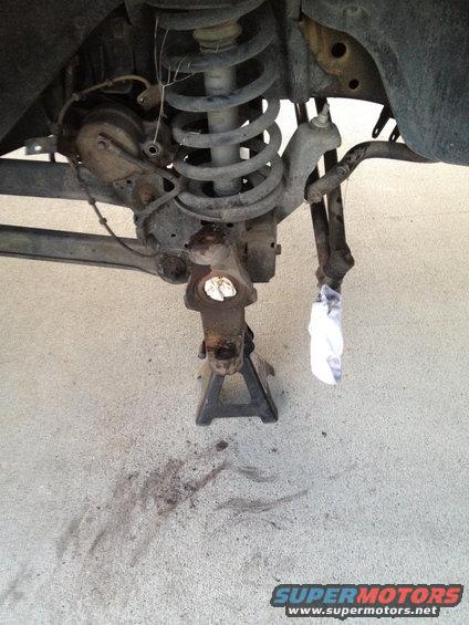 Vehicle suspension assembly supported by a jack stand, with brake components and coil spring visible