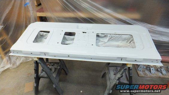 White tailgate with three rectangular window cutouts, resting on sawhorses