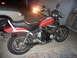 1983 Honda CB550 - A red motorcycle with exposed engine components sits parked in a garage, with a car partially visible to its left.
