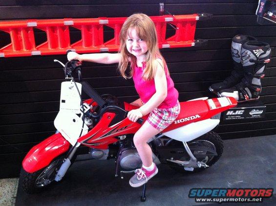 Child sits on a red Honda dirt bike with white number plate