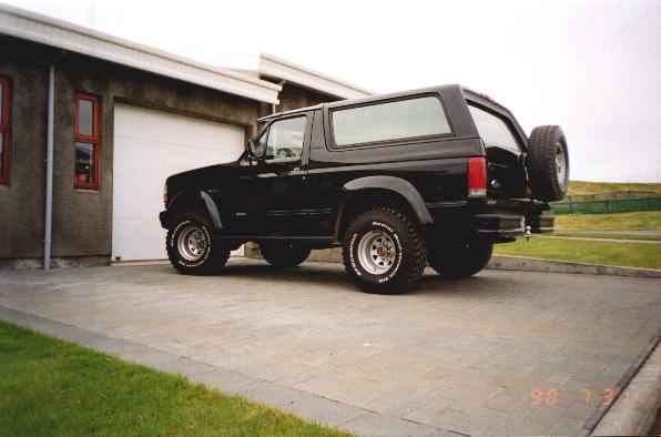 Black SUV parked on a paved driveway in front of a garage