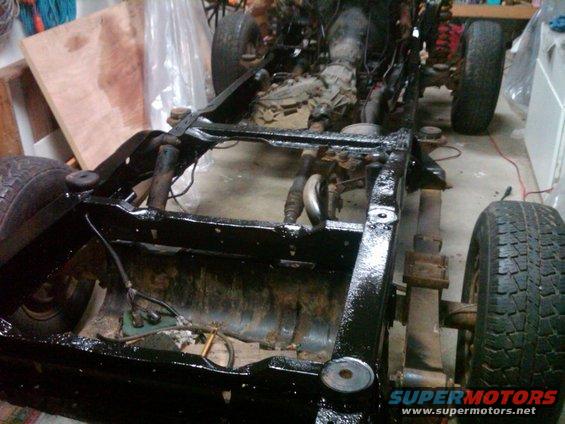 Vehicle frame with engine and drivetrain components visible, undergoing restoration