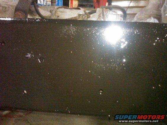 Dark painted metal frame with white speckles and a bright light reflection