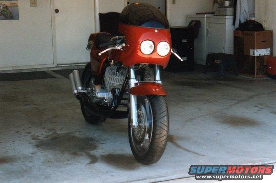 Front view of a red motorcycle with a fairing and dual headlights parked in a garage