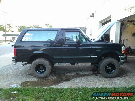 Black 1995 Ford Bronco parked outside a garage with the hood up