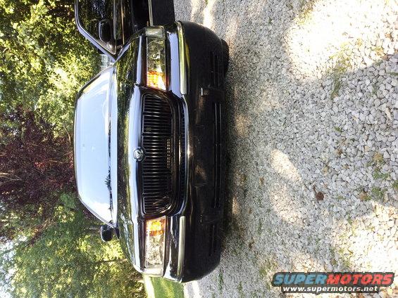 Black 1998 Mercury Grand Marquis parked on gravel with trees in background