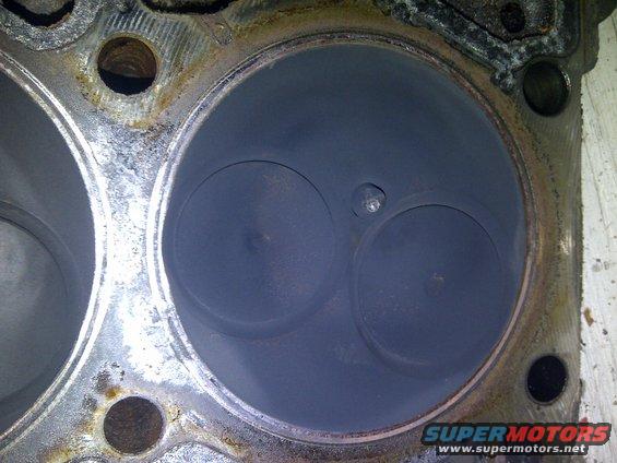 Engine cylinder head with two valves, showing carbon buildup