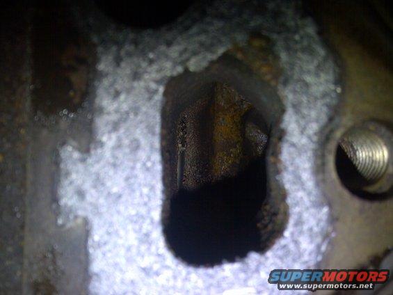 Close-up of a rusty engine cylinder bore with a threaded bolt hole visible