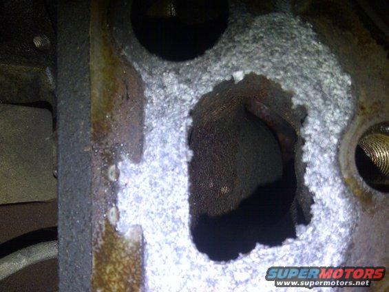 Close-up of damaged engine cylinder head with corrosion and a hole