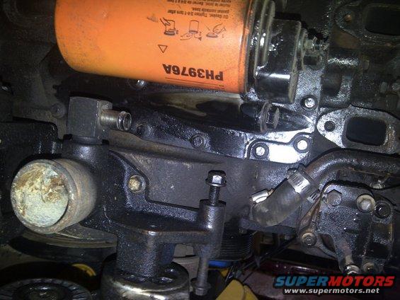 Engine block with orange oil filter labeled PH3976A, hoses, and metal fittings