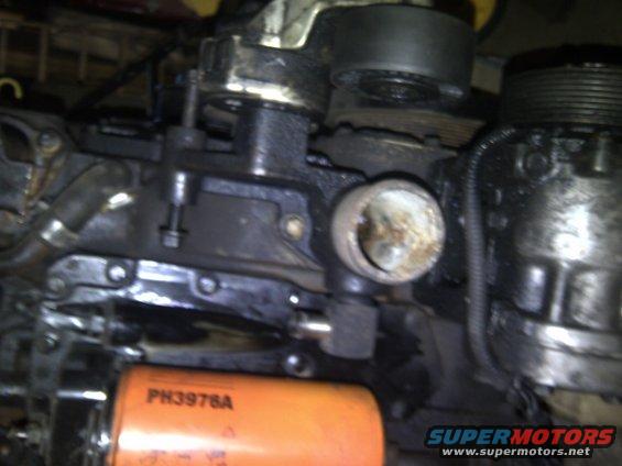 Close-up of an engine component with an orange oil filter labeled PH3976A in the foreground