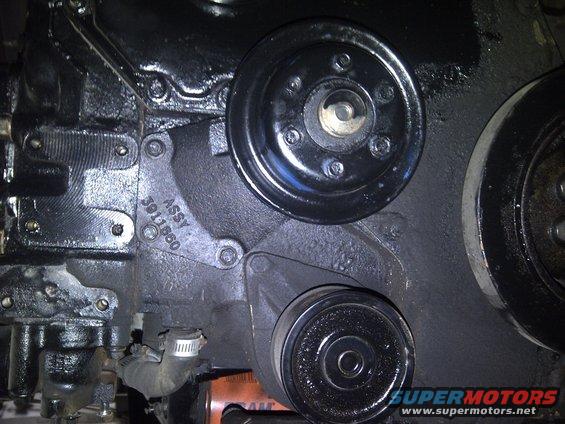Black engine block with ASSY 3911860 stamped, showing two pulleys and an oil filter