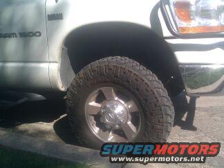 White Dodge Ram 1500 truck front wheel and fender, chrome bumper, off-road tire