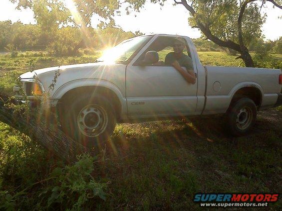 Guy in a silver pickup truck parked in a grassy area with trees