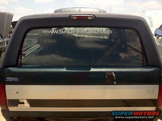 1989 Ford Bronco rear with a dark green body and a silver stripe, black camper shell, and a website sticker