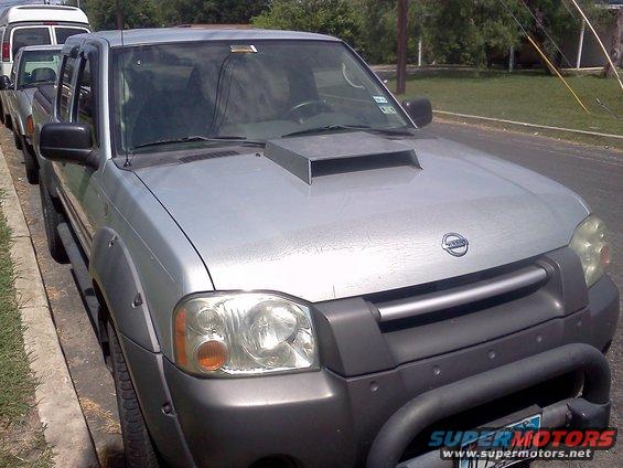 Silver Nissan pickup truck with a hood scoop and fender flares parked on a street