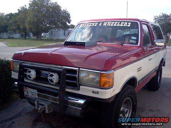 Red and white 1989 Ford Bronco with hood scoop and off-road lights