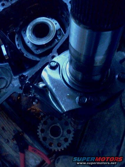 Close-up of a metal automotive transmission component with gears and a shaft, showing some damage