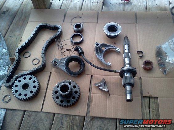 Transmission parts including a timing chain, gears, and shafts laid out on cardboard