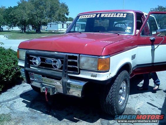 1987 Ford Bronco, red and white, with grille guard, winch, and "WEEKEND 4 WHEELERS" banner