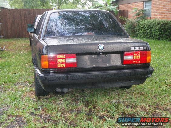 1991 BMW 325i sedan rear view, black paint, dual exhaust pipes visible