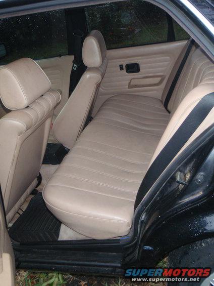 Back seat and door panel of a car with tan upholstery