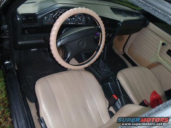 1991 BMW 3 Series interior with tan seats, beige steering wheel cover, and dashboard gauges
