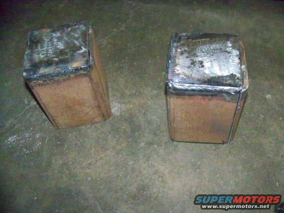 Two welded metal blocks with rough surfaces sit on a concrete floor
