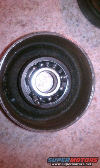 Wheel bearing inside a metal housing, showing ball bearings and a damaged retainer clip
