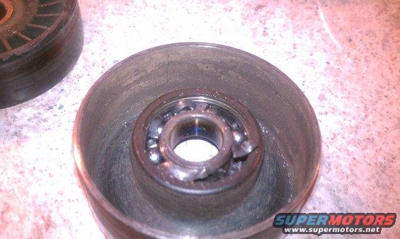 Damaged pulley bearing with visible ball bearings and metal fragments