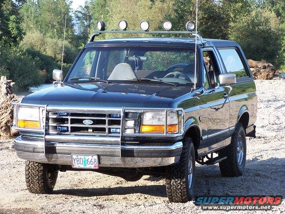 1995 Ford Bronco front view, dark green with off-road lights and tires