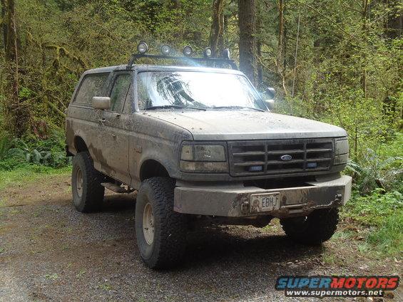 1995 Ford Bronco with off-road tires and roof lights parked on a dirt road