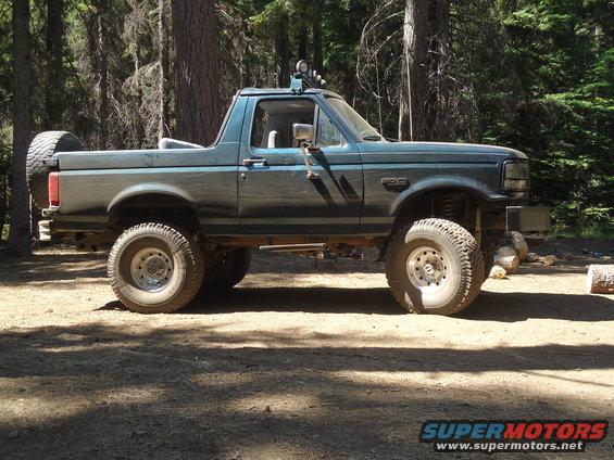 Teal lifted 1995 Ford Bronco side view with spare tire on back