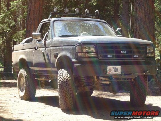 1995 Ford Bronco with aftermarket lights on roof rack, lifted suspension, and off-road tires