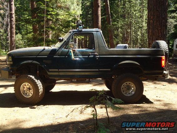 Dark green and gray 1995 Ford Bronco with off-road tires, lifted suspension, and spare tire mounted on the rear
