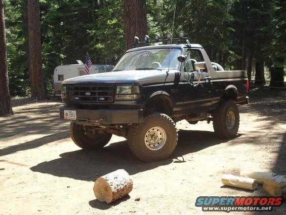Lifted 1995 Ford Bronco 3q-front view, dark blue and silver with off-road lights
