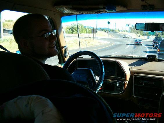 Driver in glasses looks out window of van, highway ahead