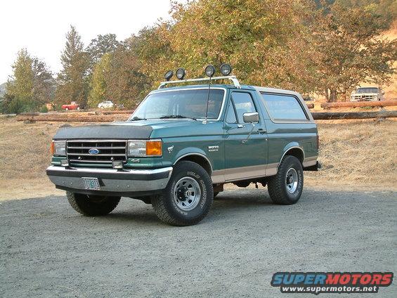 Green 1990 Ford Bronco with roof rack and spotlights parked outdoors