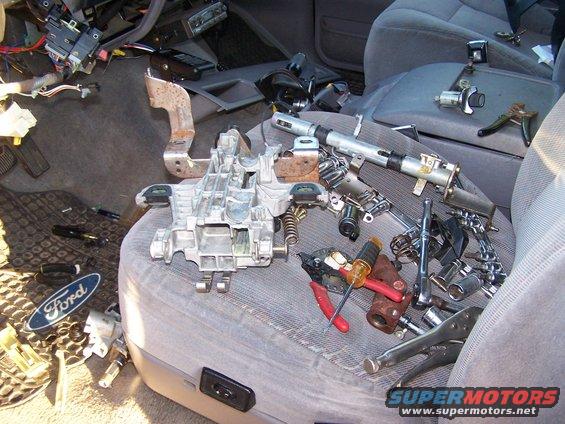 car interior with steering column parts and tools spread on seats and floor
